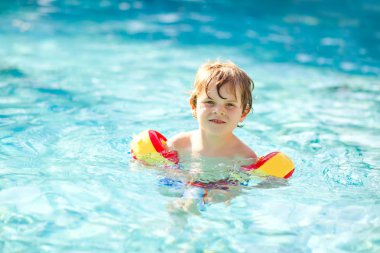 Mutlu küçük çocuk çocuk yüzme havuzuna eğleniyor. Yüzmeyi öğrenme etkin mutlu sağlıklı okul öncesi çocuk. güvenli floaties veya swimmies ile. Aile, tatil, yaz konsepti