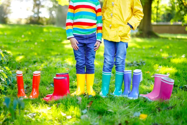 Little kids, boys and girls in colorful rain boots. Close-up of children in different rubber boots, jeans and jackets. Footwear for rainy fall — Stock Photo, Image