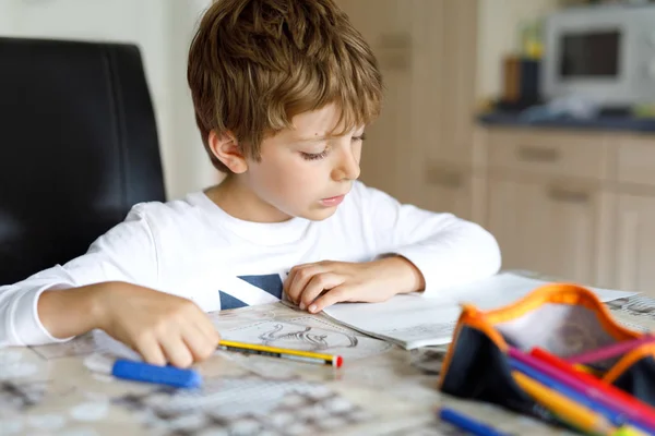 Niño cansado en casa haciendo deberes por la mañana antes de que empiece la escuela. Niño haciendo ejercicio, en el interior. Escuela primaria y educación. — Foto de Stock