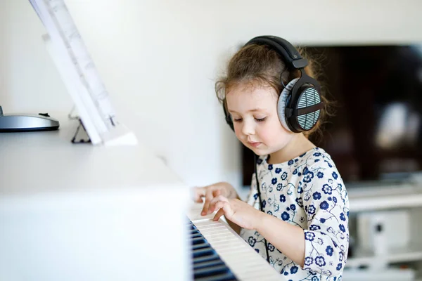 Hermosa niña tocando el piano en la sala de estar o la escuela de música. Niños en edad preescolar se divierten aprendiendo a tocar instrumentos de música. Educación, concepto de habilidades — Foto de Stock