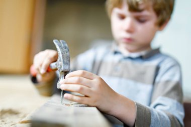 Şantiyede oyuncak aletlere yardım eden küçük çocuk. Altı yıllık komik bir çocuk yeni bir aile evi inşa ederken eğleniyor. Çivi ve çekiçli çocuk babasının eski evi yenilemesine yardım ediyor..