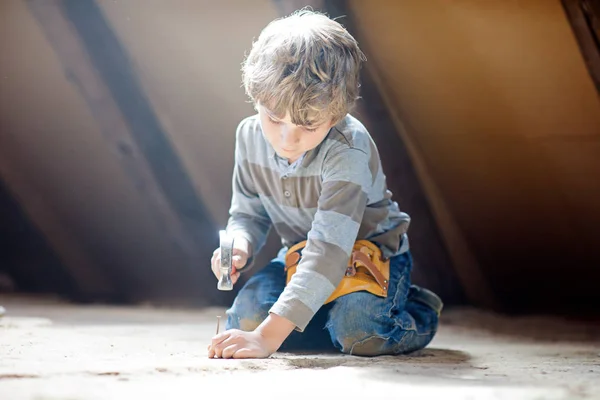 Menino ajudando com ferramentas de brinquedo no canteiro de obras. Criança engraçada de 6 anos se divertindo na construção de uma nova casa de família. Criança com unhas e martelo ajudando o pai a renovar a casa velha. — Fotografia de Stock