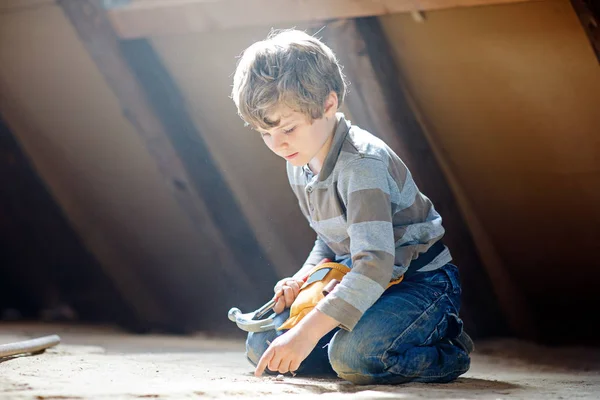 Menino ajudando com ferramentas de brinquedo no canteiro de obras. Criança engraçada de 6 anos se divertindo na construção de uma nova casa de família. Criança com unhas e martelo ajudando o pai a renovar a casa velha. — Fotografia de Stock