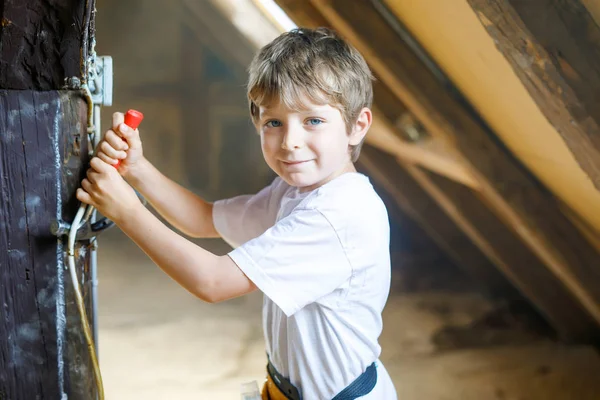 Menino ajudando com ferramentas de brinquedo no canteiro de obras. Criança engraçada de 6 anos se divertindo na construção de uma nova casa de família. Criança com unhas e martelo ajudando o pai a renovar a casa velha. — Fotografia de Stock