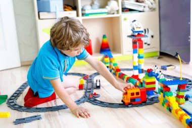 Renkli plastik bloklarla oynama ve tren istasyonu oluşturma sevimli küçük sarışın çocuk çocuk. Tren oyuncak ev bina ile eğleniyor çocuk..