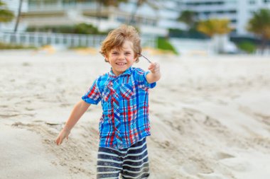 Okyanus sahilinde küçük mutlu bir çocuğun portresi. Komik şirin çocuk tatil yapıyor ve yazın tadını çıkarıyor. Fırtınalı bir günde Miami sahilinde sağlıklı bir çocuk..