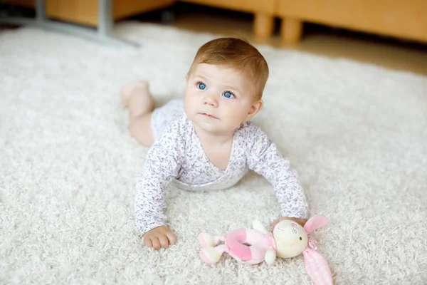 Adorable crawling baby girls portrait at home. Little funny girl lifting body and learning to crawl. Portrait of beautiful baby with blue eyes, child playing — Stock Photo, Image