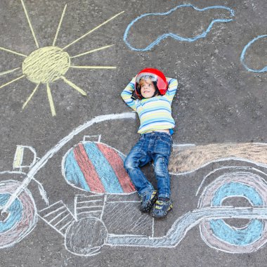 Çocuklar için yaratıcı eğlence: motosiklet resim ile renkli tebeşirler çizim ile eğleniyor kask içinde dört yıllık komik küçük çocuk. Çocuklar, yaşam tarzı, eğlence kavramı