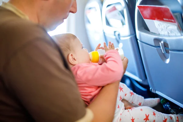 Joven padre cansado y su hija llorando durante el vuelo en avión de vacaciones. Papá sosteniendo a la niña del brazo. Viajes aéreos con concepto de bebé, niño y familia — Foto de Stock