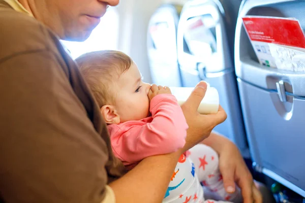 Young moe vader en dochter met huilende baby tijdens de vlucht op het vliegtuig op vakantie te gaan. Vader babymeisje op de arm houden. Vliegreizen met baby, kind en gezin concept — Stockfoto