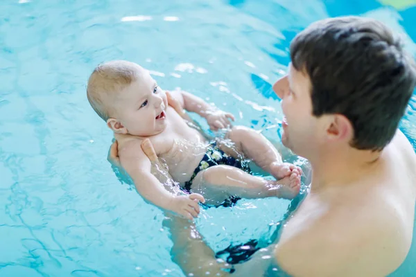 Happy middle-aged father swimming with cute adorable baby in swimming pool. Smiling dad and little child, newborn girl having fun together. Active family spending leisure and time in spa hotel — Stock Photo, Image