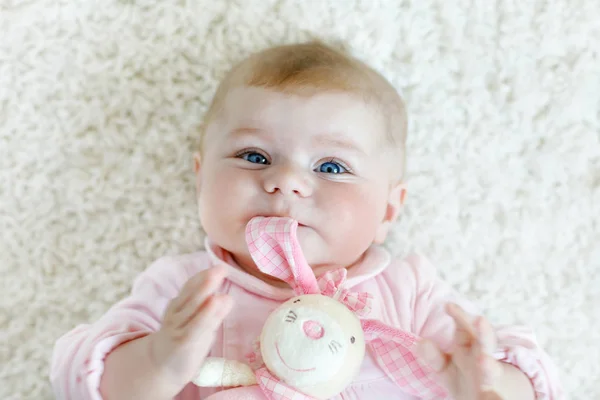 かわいいかわいいの生まれたばかりの赤ちゃんはカラフルなパステル調の豪華なウサギのおもちゃで遊ぶ。新しい子、カメラを見ている小さな女の子。赤ちゃん学習グラブ. — ストック写真