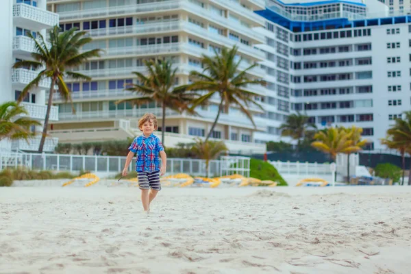 Retrato de un niño feliz en la playa del océano. Divertido lindo niño haciendo vacaciones y disfrutando del verano. Niño sano en la playa de Miami EE.UU. en un día ventoso tormentoso. —  Fotos de Stock