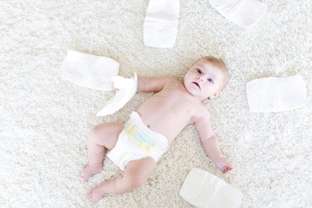 Cute adorable newborn baby of 3 moths with diapers. Hapy tiny little girl or boy looking at the camera. Dry and healthy body and skin for children concept. Baby nursery.