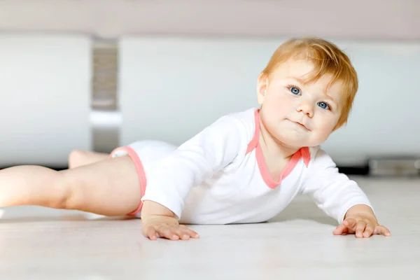 En liten søt jente som lærer å krabbe. Frisk unge som kryper på barneværelset. En glad, sunn småbarnsjente. Søtt småbarn som oppdager hjemmet og lærer seg forskjellige ferdigheter – stockfoto