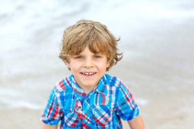 Okyanus sahilinde küçük mutlu bir çocuğun portresi. Komik şirin çocuk tatil yapıyor ve yazın tadını çıkarıyor. Fırtınalı bir günde Miami sahilinde sağlıklı bir çocuk..