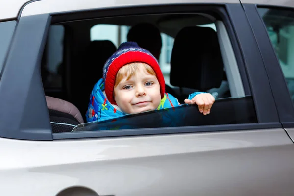 Retrato de uma criança bonita sentada na cadeirinha. Segurança no transporte de crianças. Bonito menino saudável olhando feliz sobre férias em família com carro através da janela durante a pé em engarrafamento — Fotografia de Stock