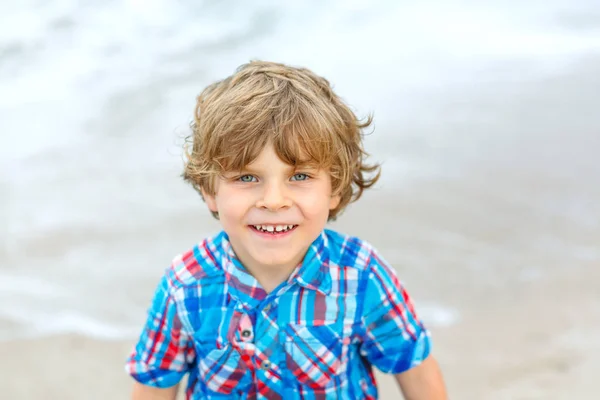 Retrato de un niño feliz en la playa del océano. Divertido lindo niño haciendo vacaciones y disfrutando del verano. Niño sano en la playa de Miami EE.UU. en un día ventoso tormentoso. — Foto de Stock