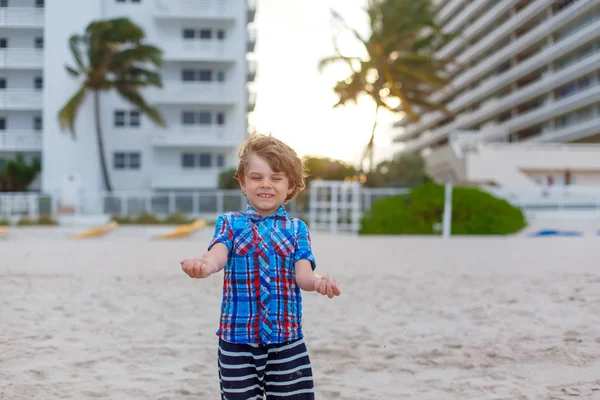 Portret szczęśliwego chłopca na plaży oceanu. Śmieszne słodkie dziecko robi wakacje i ciesząc się latem. Zdrowy chłopiec na plaży Miami USA w burzliwy wietrzny dzień. — Zdjęcie stockowe