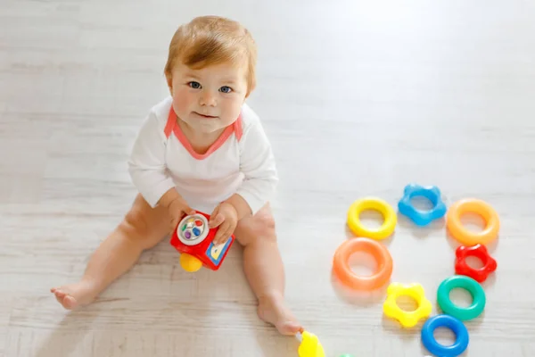 Adorable baby girl playing with educational toys in nursery. Happy healthy child having fun with colorful different toys at home. Kid trying to build plastic pyramid and using blocks with letters — Stock Photo, Image