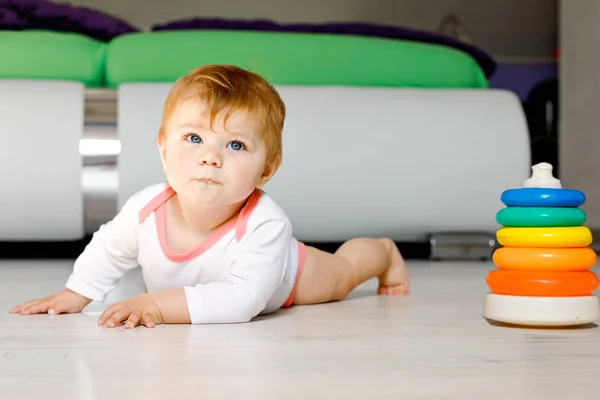 Little cute baby girl learning to crawl. Healthy child crawling in kids room. Smiling happy healthy toddler girl. Cute toddler discovering home and learning different skills.