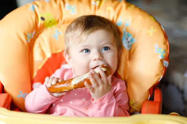 Linda niñita comiendo pan. Niño comiendo por primera vez trozo de pretzel. Primer alimento después de amamantar. Bebé saludable divirtiéndose . — Foto de Stock