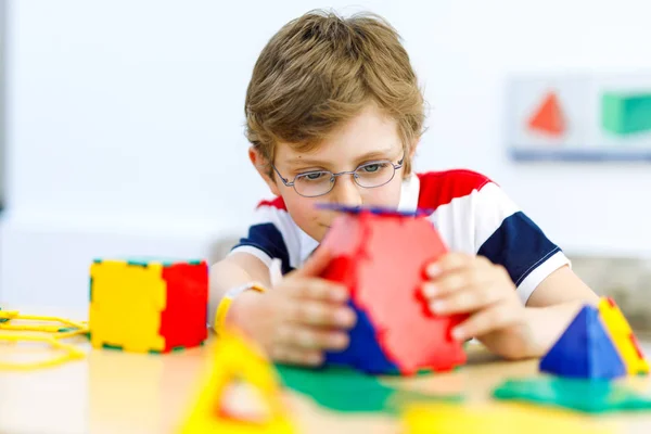 Menino feliz com óculos se divertindo com a construção e criação de figuras geométricas, aprendendo matemática e geometria — Fotografia de Stock