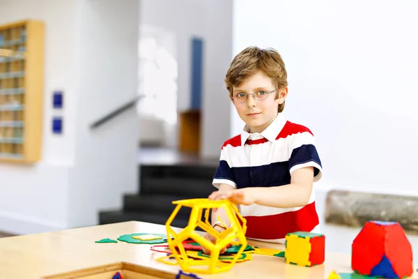 Happy kid jongen met bril veel plezier met het bouwen en maken van geometrische figuren, leren wiskunde en meetkunde — Stockfoto