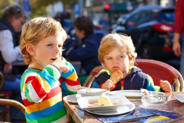 Çok güzel iki açık kafede dondurma yeme çocuklar çocuk. Güneşli mutlu bir aile. Sağlıklı çocuklar, İkizler ve arkadaşlarım gelateria restoran tatlı tatlı ile
