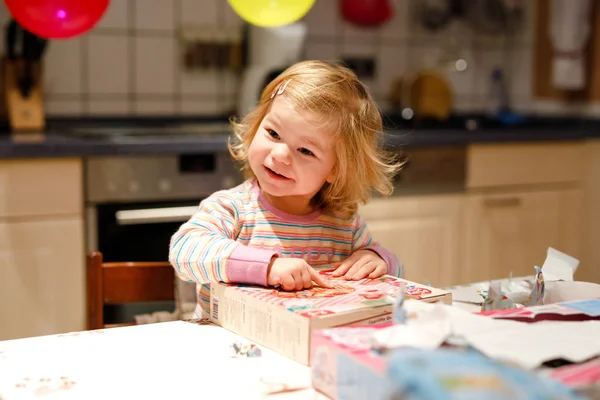 Adorable niñita celebrando su segundo cumpleaños. Bebé niño desempacando regalos. Feliz niño sano es sorprendido acerca de grandes cajas y juguetes presentes —  Fotos de Stock