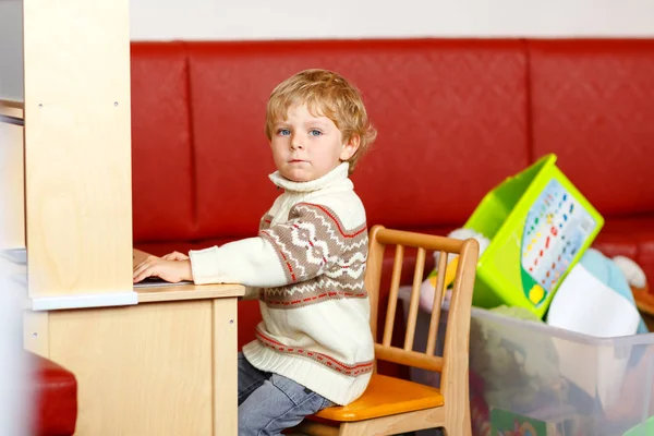 Glad rolig lite blont barn leker med massor av pedagogiska leksaker och bilar inomhus. Kid pojke bär färgglada kläder och att ha kul på dagis. Barn ha roligt i rum hemma. — Stockfoto