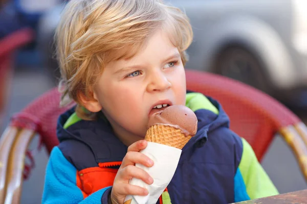 Lindo niño adorable comer helado en la cafetería al aire libre. Feliz niño en un día soleado. Niño sano con postre dulce en restaurante de gelatería —  Fotos de Stock