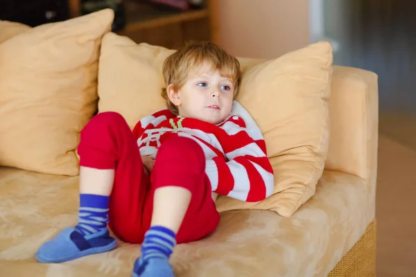 Boldog imádnivaló gyerek fiú fekve nézi a televíziót. Vicces egészséges gyermek élvezi a rajzfilmek. Függőség fogalma. Kisgyermek látszó mutatja, és a film a tv otthon. — Stock Fotó