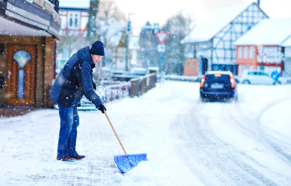 在冬天下雪的时候，拿着铲子的人清扫人行道。欧洲的冬季。穿着温暖冬衣的年轻人。德国的雪和天气混乱。暴风雪和大雪。Schneechaos案 — 图库照片