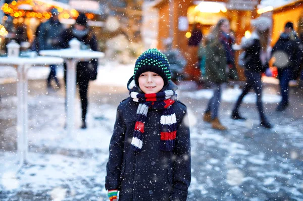 Der kleine süße Junge hat seinen Spaß auf dem deutschen Weihnachtsmarkt. glückliches Kind auf dem traditionellen Familienmarkt in Deutschland, lachender Junge in bunter Winterkleidung — Stockfoto