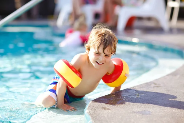 Šťastné dítě chlapec baví v plaveckém bazénu. Aktivní šťastné dítě naučit se plavat. s bezpečnou floaties nebo swimmies. Rodina, dovolená, letní koncepce — Stock fotografie