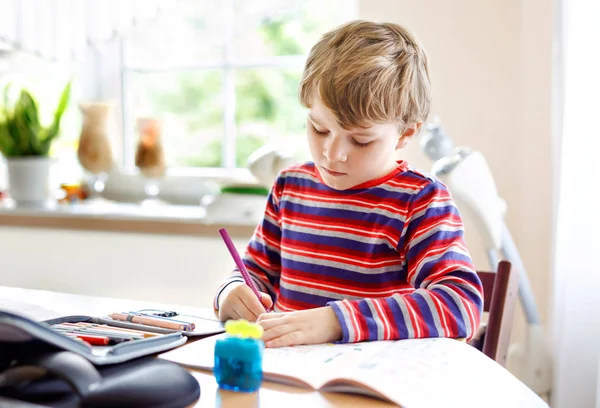 在开学前的早上，在家里做作业的快乐微笑的小男孩。小孩子在屋里做运动。小学和教育：男孩画出几何图形 — 图库照片