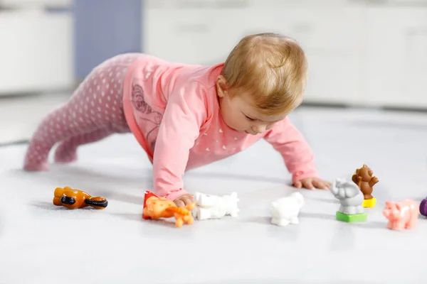 Adorable niña jugando con mascotas de juguete doméstico como vaca, caballo, oveja, perro y animales salvajes como jirafa, elefante y mono. Feliz niño sano divirtiéndose con coloridos juguetes diferentes en casa —  Fotos de Stock