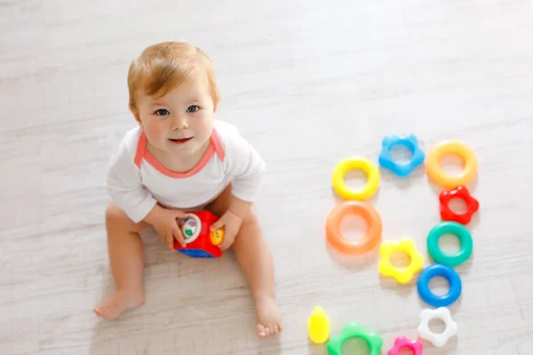 Bebek kız kreş eğitici oyuncaklar ile oynama. Mutlu sağlıklı çocuk evde renkli yumuşak oyuncaklar ile eğleniyor. Evlat plastik piramit inşa etmeye ve harflerle bloğu kullanma — Stok fotoğraf