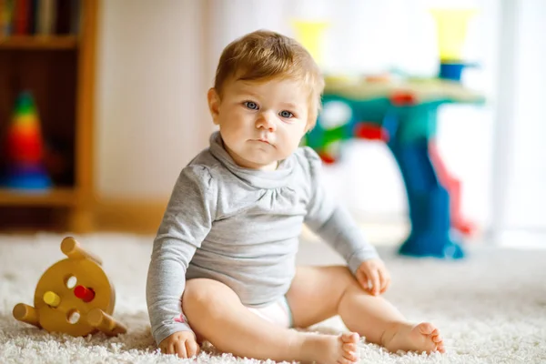 Entzückendes kleines Mädchen, das mit Lernspielzeug spielt. Fröhliches gesundes Kind, das sich zu Hause mit buntem Holzspielzeug vergnügt. Frühe Entwicklung für Kinder mit Naturspielzeug. — Stockfoto