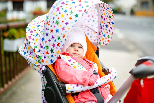 秋天的一天,可爱的小女孩坐在婴儿车或婴儿车里.健康快乐的孩子穿着保暖的衣服在新鲜空气中散步。孩子，黄色的秋天枫树，五彩缤纷 — 图库照片