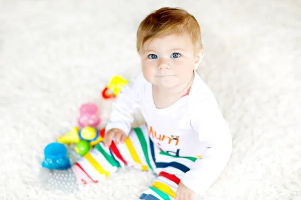 Adorável menina brincando com brinquedos educativos no berçário. Criança saudável feliz se divertindo com brinquedos diferentes coloridos em casa. Desenvolvimento do bebê e primeiros passos, aprendendo a jogar e agarrar. — Fotografia de Stock