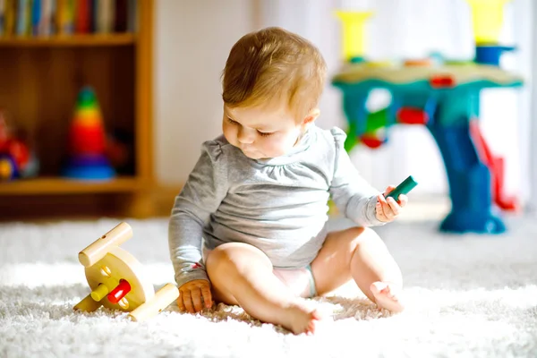 Чарівна дівчинка грає з освітніми іграшками. Щаслива здорова дитина розважається з різнокольоровою дерев'яною іграшкою вдома. Ранній розвиток для дітей з натуральною іграшкою . — стокове фото