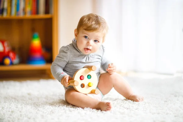 教育用のおもちゃで遊んでいる愛らしい赤ちゃんの女の子。家でカラフルな異なる木製のおもちゃで楽しんでいる幸せな健康的な子供。自然のおもちゃを持つ子供たちのための初期の開発. — ストック写真