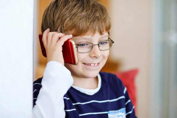 En söt liten pojke med glasögon som talar i mobiltelefon. Bedårande friska barn som håller smartphone och prata med en flicka vän eller med föräldrar, morföräldrar. — Stockfoto