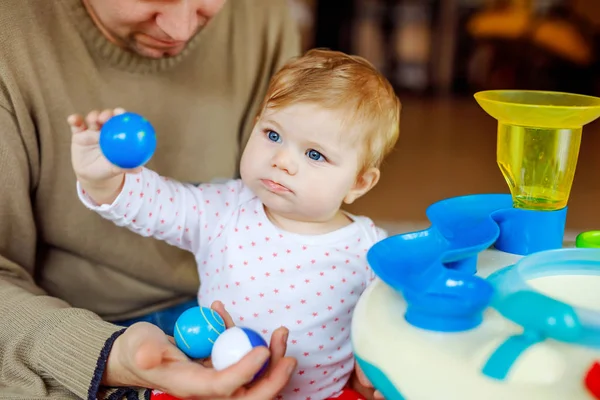 Gelukkig trotse jonge vader plezier met baby dochter, familieportret samen. Papa spelen met babymeisje met educatieve sorter speelgoed met verschillende kleurrijke ballen. Man met klein kind thuis. — Stockfoto