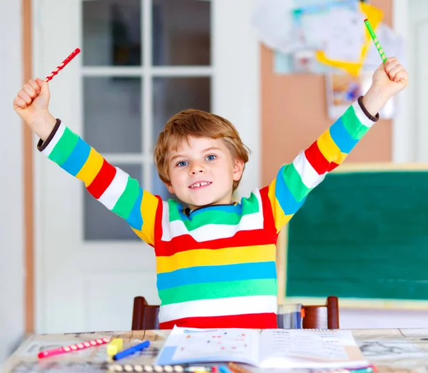 Potret lucu bahagia anak sekolah anak di rumah membuat pekerjaan rumah. Anak kecil menulis dengan pensil berwarna-warni, di dalam ruangan. Sekolah dasar dan pendidikan — Stok Foto