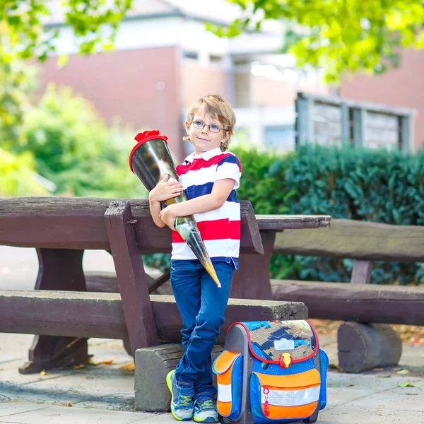 Happy little kid boy with glasses and backpack or satchel on his first day to school . Child outdoors on warm sunny day, Back to school concept. Kid with traditional schoolbag in German Schultuete. — Stock Photo, Image