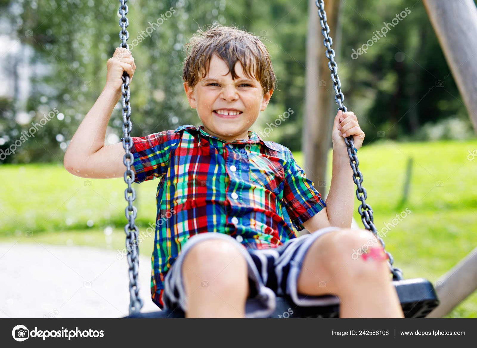 Funny kid boy having fun with chain swing on outdoor playground while being wet splashed with Funny kid boy having fun with chain swing on outdoor playground while being wet splashed with