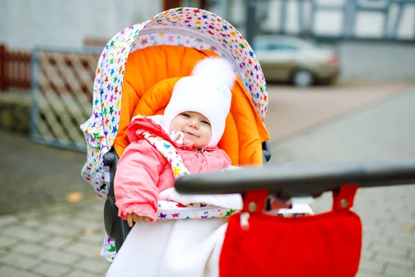 Schattig klein mooi babymeisje zittend in de kinderwagen of kinderwagen op herfstdag. Gelukkig gezond kind gaat voor een wandeling op frisse lucht in warme kleren. Baby met gele esdoorn bomen in kleurrijke kleding — Stockfoto